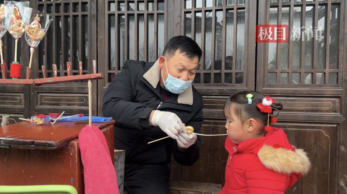 图为糖画师傅正在给小朋友制作糖人  孟莹摄.png