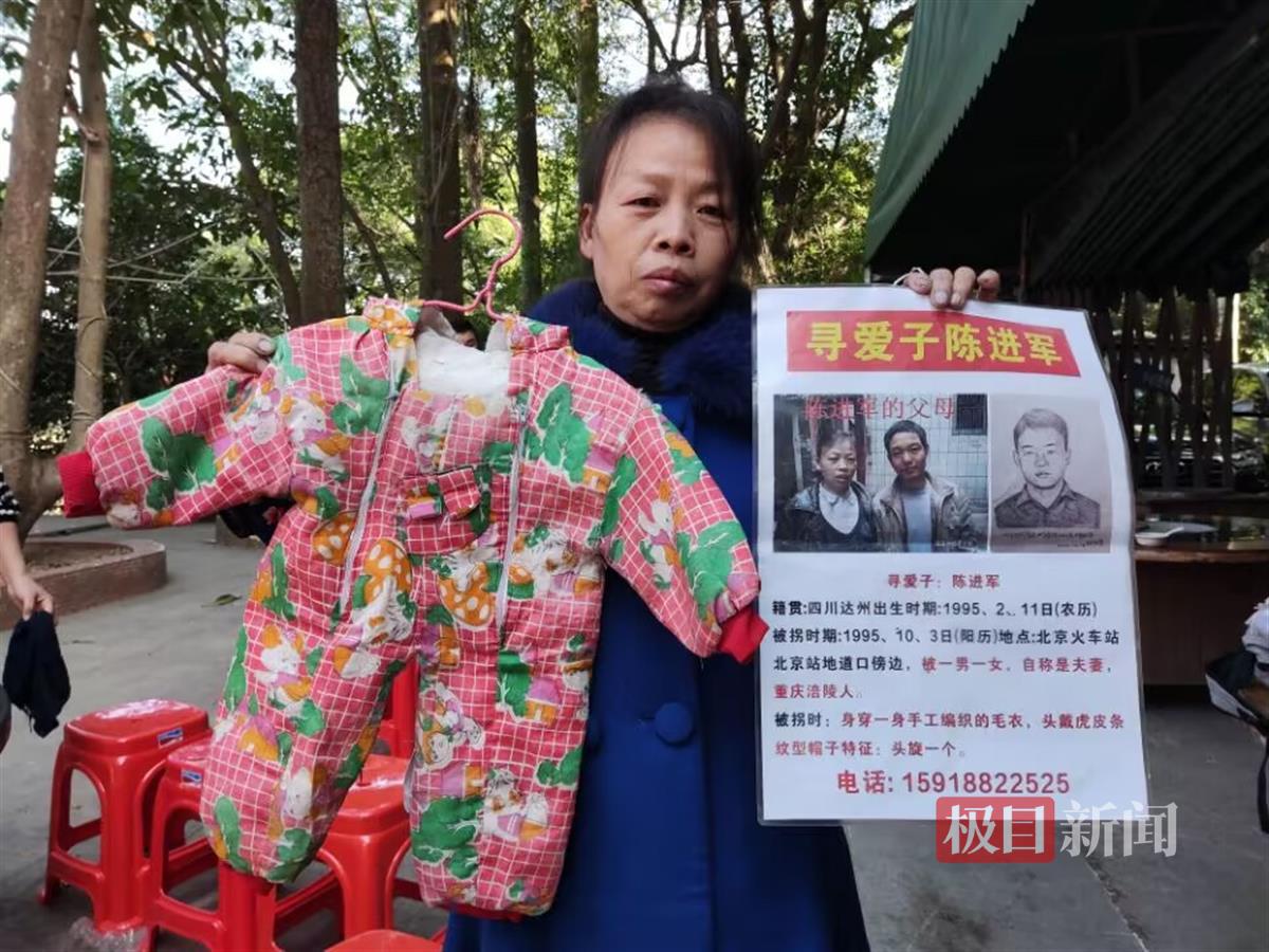 陈进军妈妈举着寻人启事和小孩曾穿过的衣服