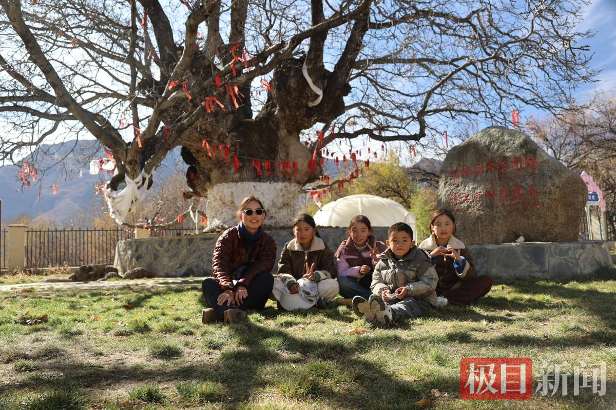 刘利平在“核桃王”大树下和藏族小朋友合影。（受访者供图）.jpg