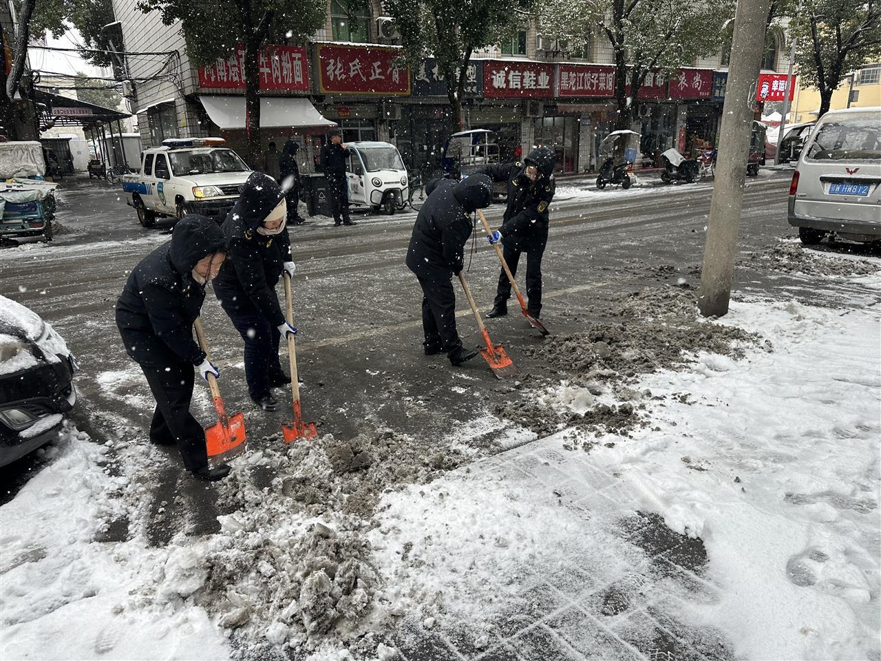执法队员挥动铁锹清理市场路积雪，保障居民出行.jpg
