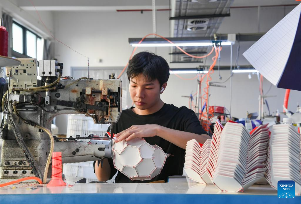 A worker making footballs at a sports goods company in Yiwu.