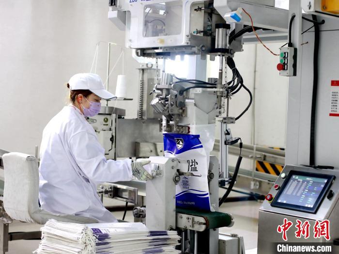 图为茶卡盐业工人正在操作装袋机。　西部矿业供图