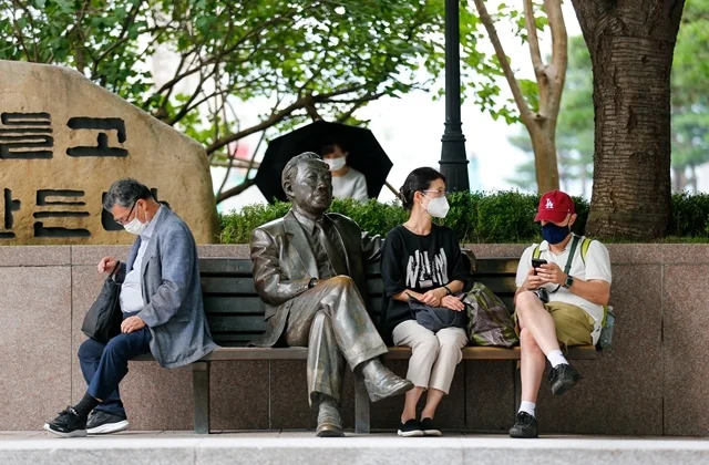 8月3日，人们佩戴口罩在韩国首尔一处公园休息。新华社