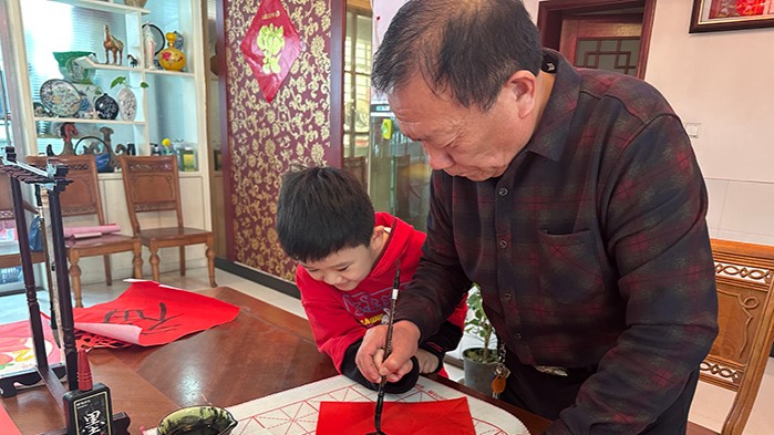 李泽楷和爷爷一起写福字（人民网 宋子节摄