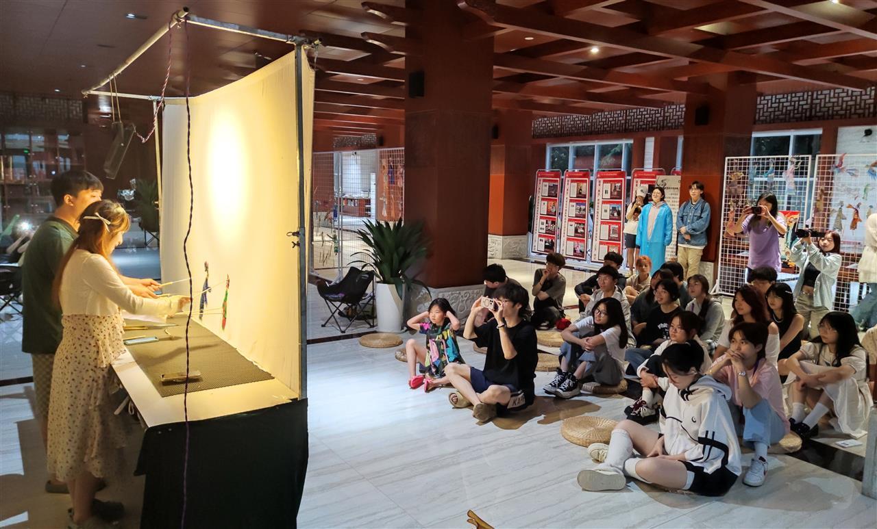 皮影劇目展出現(xiàn)場的幕后工作人員與觀眾。學(xué)校供圖.jpg