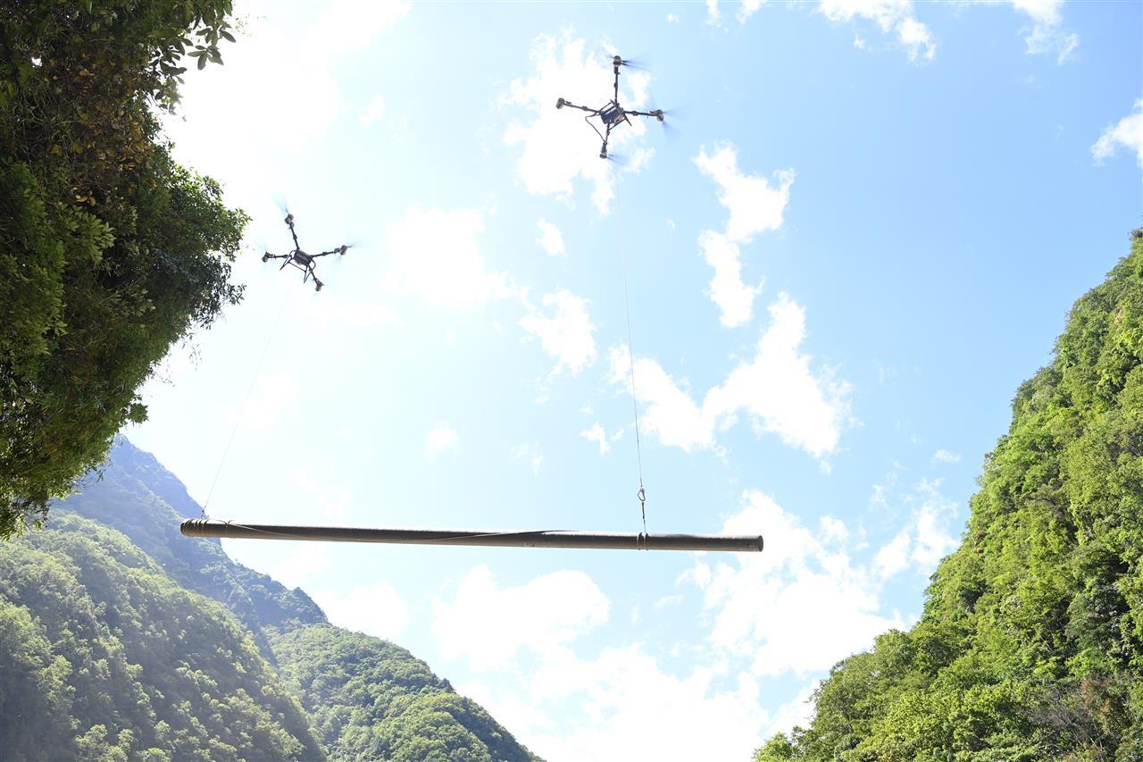 南方电网公司抢修队利用两台无人机实现双机联运，一起把电线杆调运到江对岸。 赖增鹏 摄.jpg