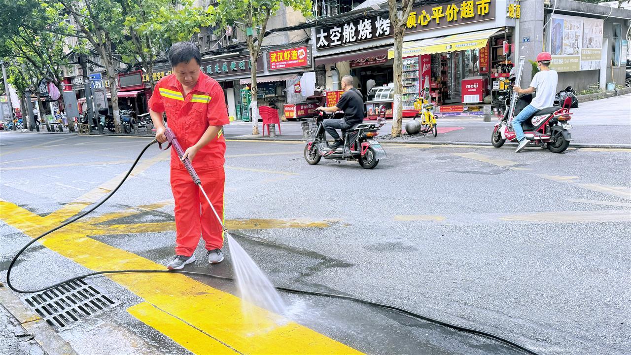 图2：六角亭街环卫工人用拖把将泡化片碱的水覆盖于污垢5到10分钟，然后用高压冲洗枪洗出本色.jpg