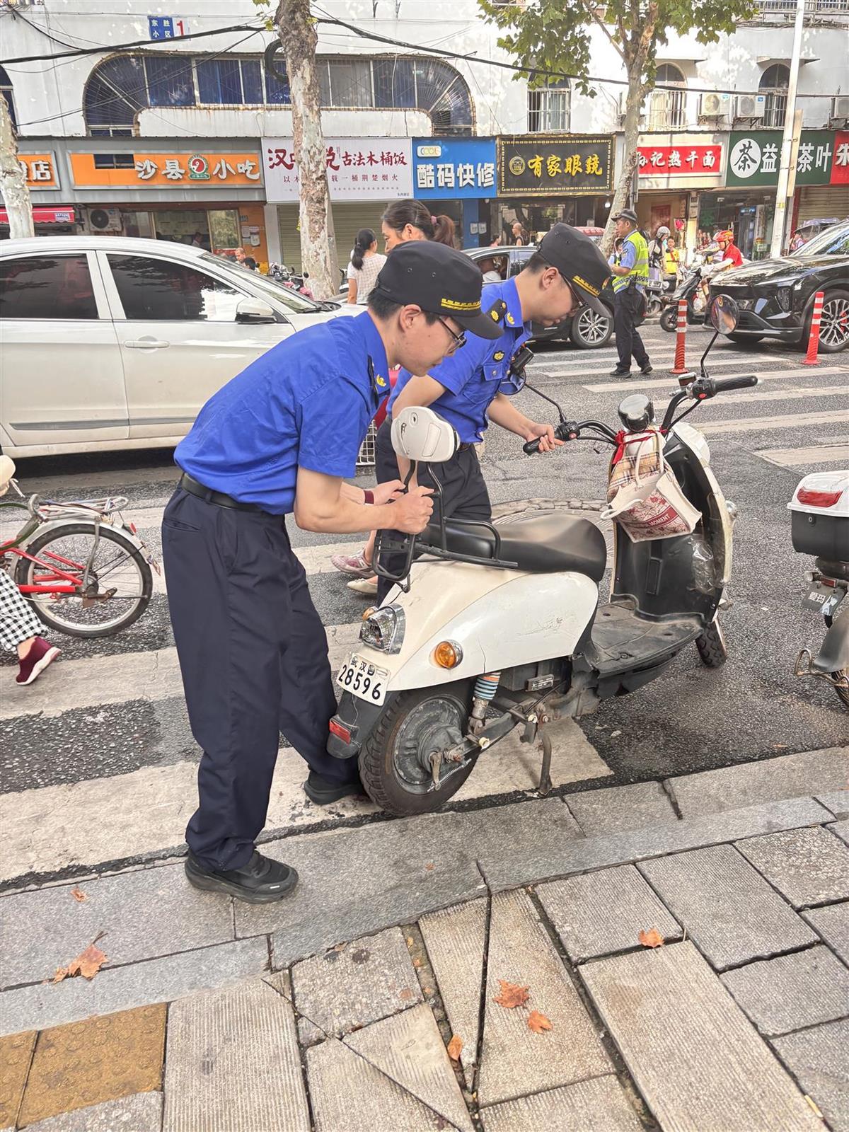 执法队员清理学校门口马路上违停的非机动车.jpg