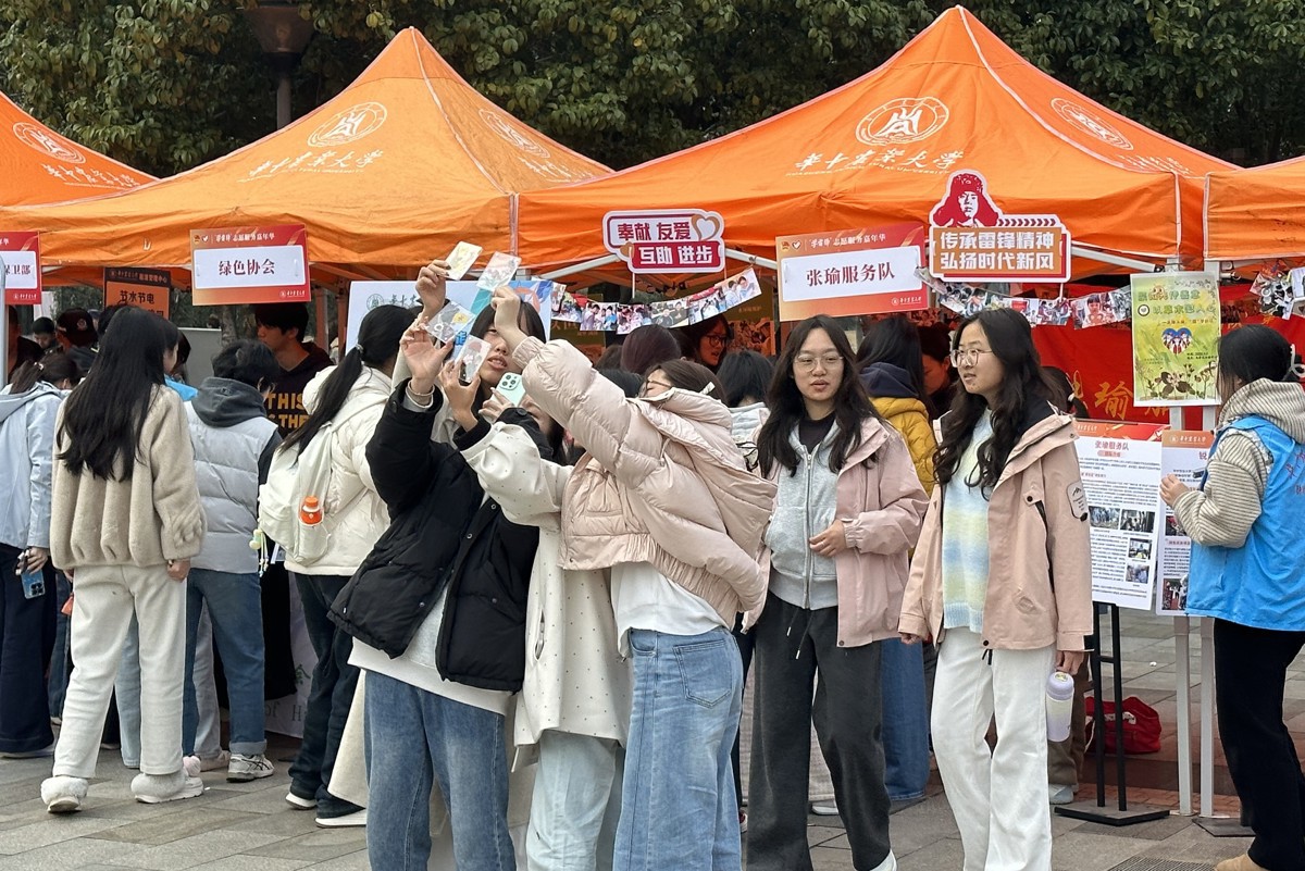 同学们在张瑜服务队摊位前展示压花冰箱贴（张妙萱 摄）.jpg