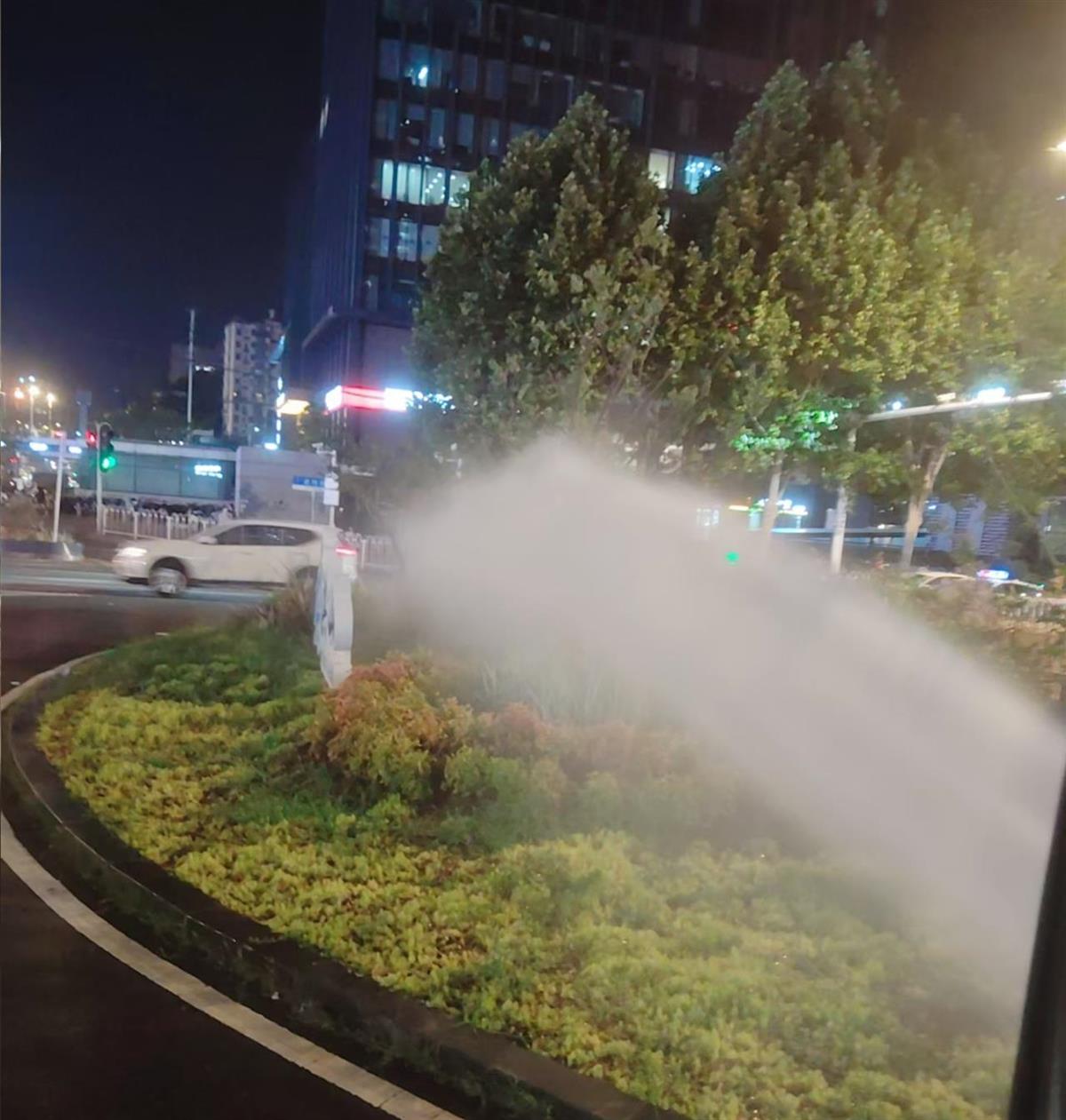 15日晚9时许，洪山园林师傅为街道口花坛喷水雾.png
