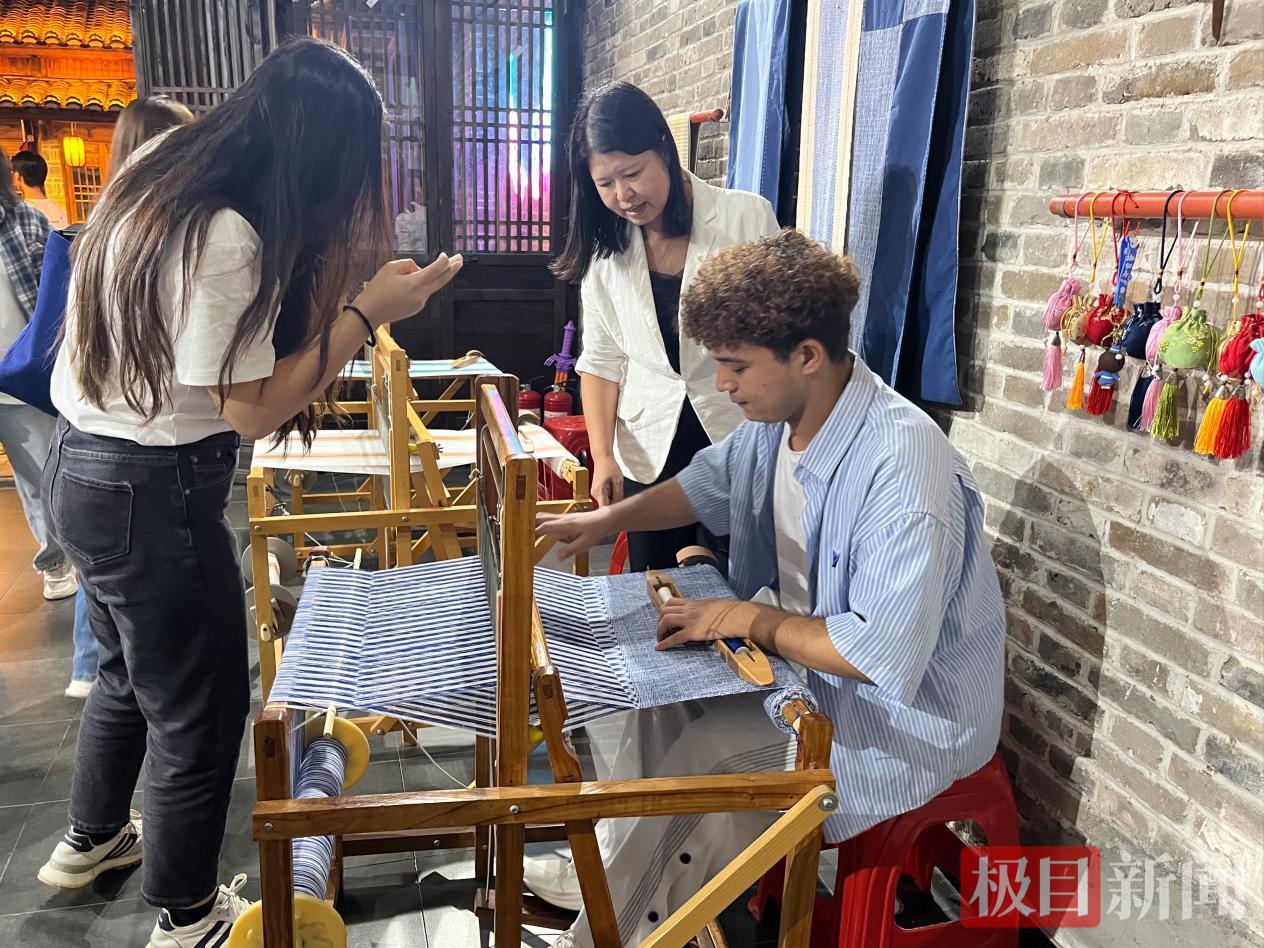 图为游客体验非遗手工织布。郧轩文摄.png