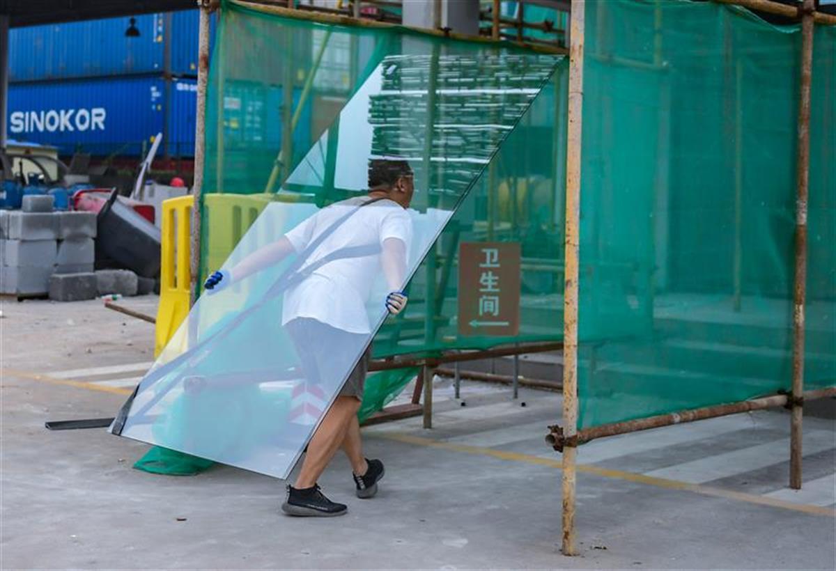 在武汉阳逻港的一装修工地,4名工人师傅正在搬运大块头装修玻璃,只见