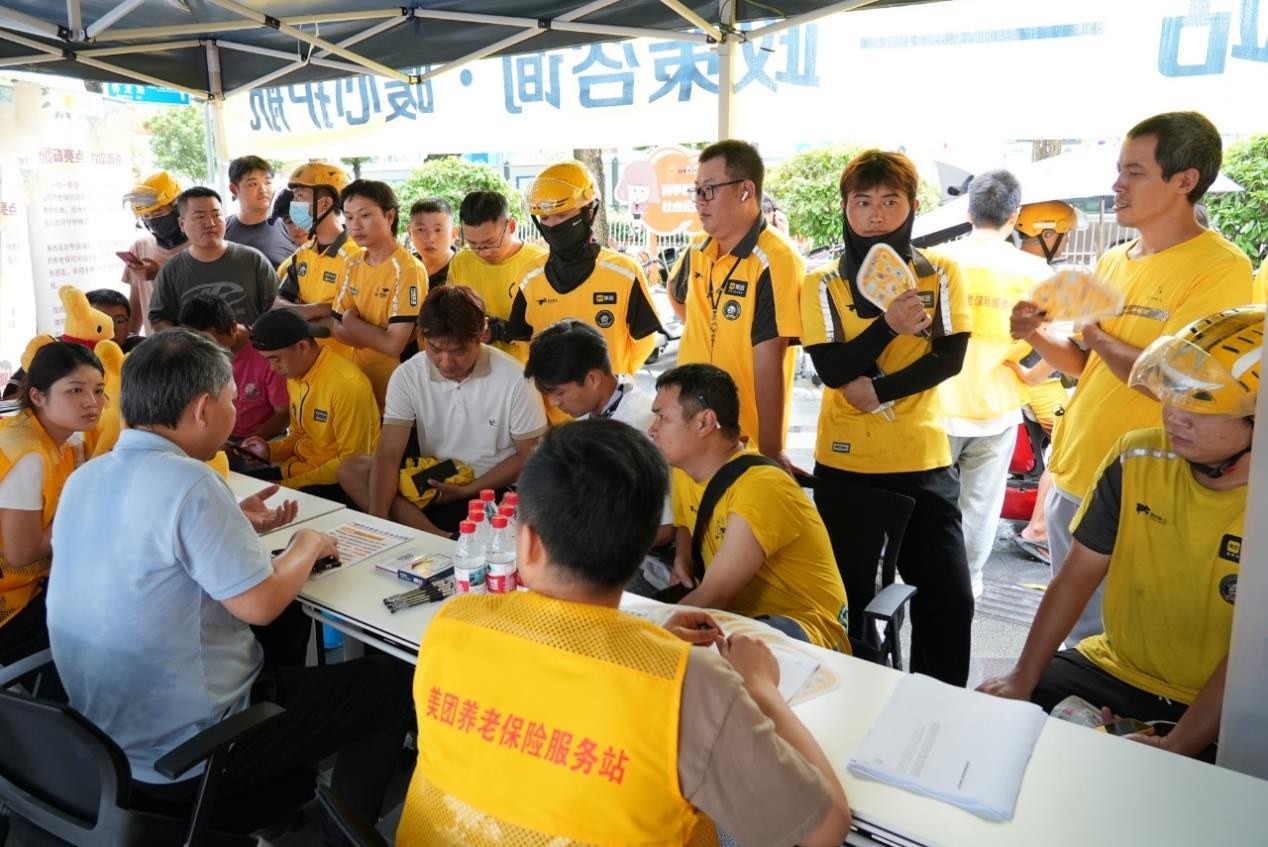 7月初，广东深圳美团骑手在街头服务站向人社部门工作人员咨询养老保险参保流程。（摄影：林书明）.png