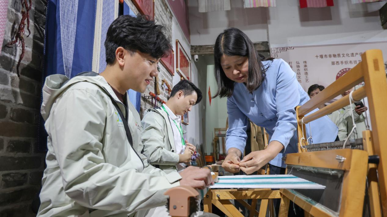 图为港澳青年在乞巧织布坊体验手工织布。徐军摄.png