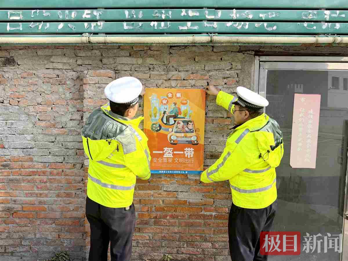 图4：交警在村里张贴交通安全海报.jpg