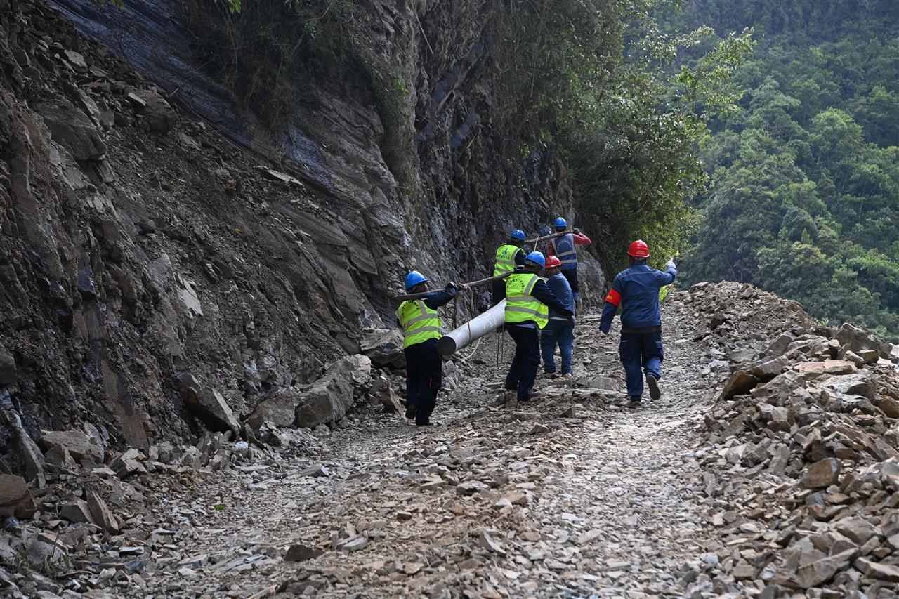 道路被泥石流冲毁，南方电网公司抢修队队员徒步把电线杆抬到安装位置。赖增鹏 摄.jpg