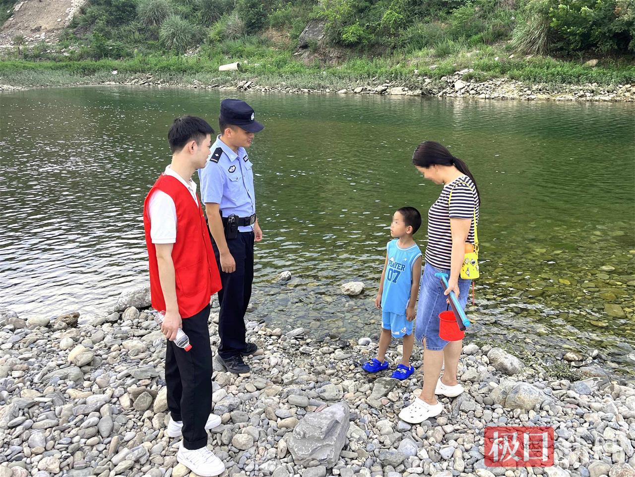 图1：民警在河边劝阻戏水儿童 .jpg