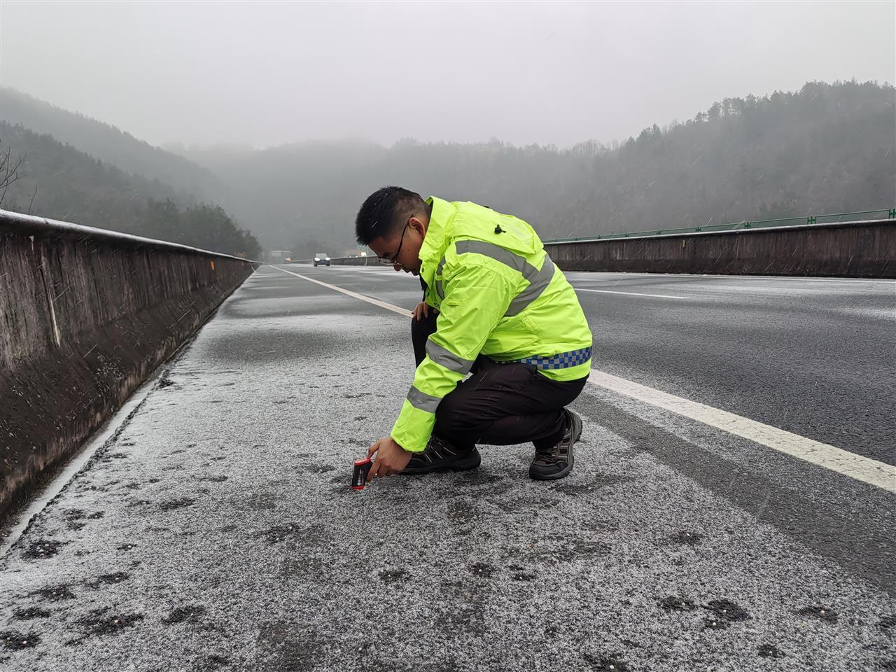 公司第四综合巡检办巡检人员正在呼北高速郧十路段上使用路面测温设备，近距离检测路面冰层厚度与温度，以评估道路通行风险，并采取相应举措高效应对寒潮天气。.jpg