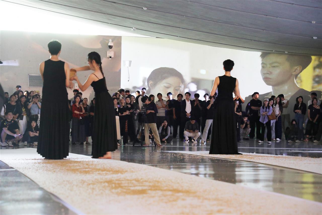 12 “稻语仪式”环节，两名舞者怀抱铜钵缓行在展厅中央两处巨型纸张上，倾倒稻米。黎艺丁 摄.JPG